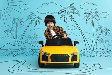 Cute little boy driving toy car and drawing of tropical resort on light blue background