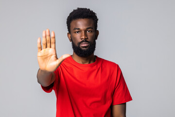 Fototapeta premium Young African man showing stop sign with hand over white background