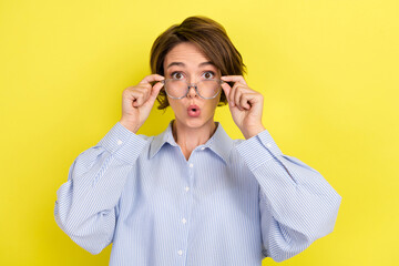 Photo of young woman amazed shocked omg wow hands touch glasses fake news isolated over yellow color background