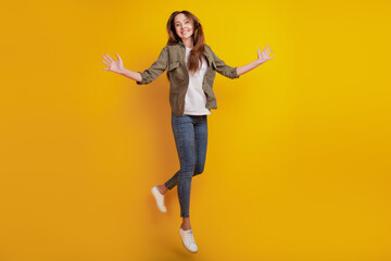 Fototapeta na wymiar Portrait of cheerful girl jumping isolated on yellow background