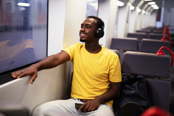 Fototapeta na wymiar Young man travel by train. Handsome african man listening the music while travel..