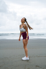 Fitness lifestyle success. Happy fit healthy woman laughing at the beach during outdoor workout.