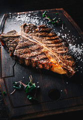 Grilled T-bone Steak on bones on wooden board on dark background