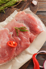 pork tenderloin with  chili pepper, onion, rosemary , salt on a dark wooden background