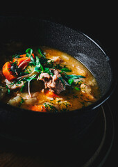 meat soup with rice and vegetables in bowl on wooden table background