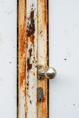 A white door with a rusted metal frame and orange and brown structures