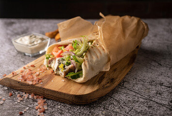 doner kebab, a shawarma in a pit of fresh vegetables and meat. with large spices. restaurant serving. on a dark background. for menus and ads