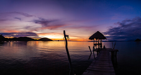 Sunset over wooden beach bar in sea and hut on pier in koh Mak island, Trat, Thailand