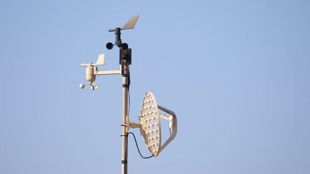 Home weather station spins in the wind against a blue sky background.