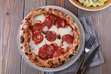 Neapolitan pizza with pepperoni and vegetable salad