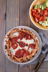 Neapolitan pizza with pepperoni and vegetable salad