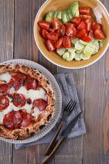 Neapolitan pizza with pepperoni and vegetable salad