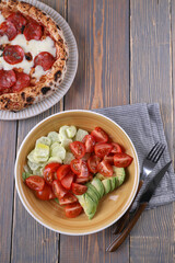 Neapolitan pizza with pepperoni and vegetable salad