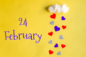 24 february day of month, colorful hearts rain from a white cotton cloud on a yellow background. Valentine's day, love and wedding concept