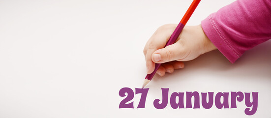 A child's hand writes 27 january in a lilac pencil. Banner with copy space