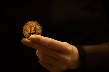 Golden btc cion in female hands on dark background