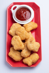 Chicken nuggets with tomato sauce in red plate