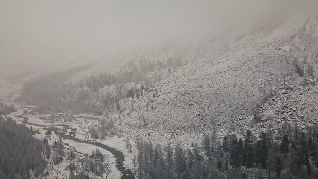 Storm, snowfall in the huge glacier of Mount Belukha, the valley of the Aktru River, the Altai Mountains. Cloudy weather, stone in the snow, storm, wildlife, winter forest, frozen mountain river in