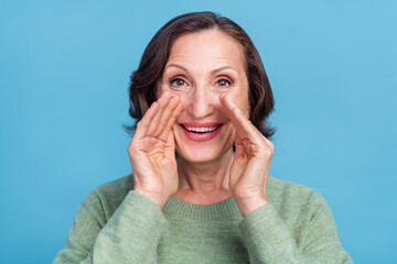 Photo of old white hair funky woman tell secret wear green sweater isolated on blue color background