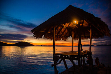 Sunset over wooden beach bar in sea and hut on pier in koh Mak island, Trat, Thailand