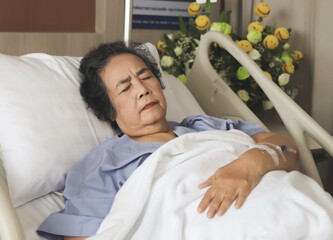 Asian senior  woman lying in hospital bed, feeling pain. Elderly health concept.