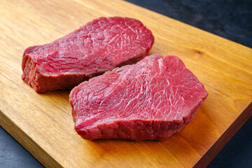 Raw dry aged bison beef rump steak piece as close-up on wooden design board
