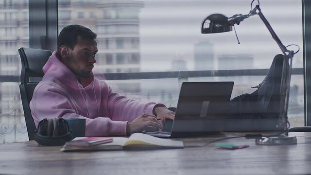 A young, handsome man works in an office space.