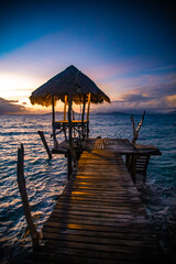Fototapeta na wymiar Sunset over wooden beach bar in sea and hut on pier in koh Mak island, Trat, Thailand