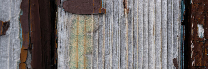 Texture of old weathered rough cracked wood surface with peeling paint. Wide panoramic rustic background for design.