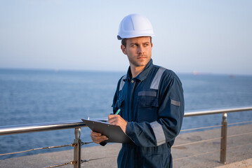 Male engineer with clipboard on pier