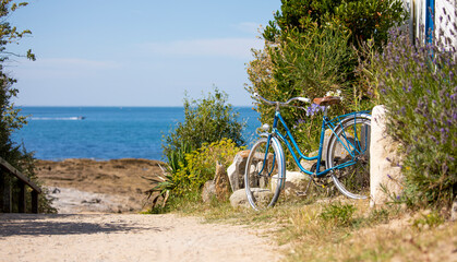 Vieux vélo bleu en bord de mer sur une plage de Bretagne en France.