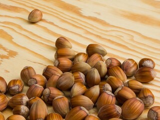 Hazelnuts in shells scattered on a wooden table top.