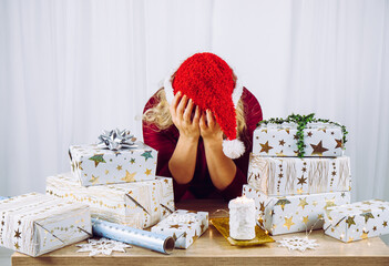 Unrecognizable woman housewife tired of wrapping Christmas presents in home. Stacks of gifts....