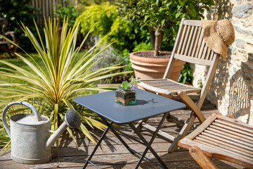 Salon de jardin sur une terrasse en bois dans un charmant jardinet au printemps.