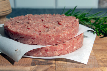 Organic ground beef patties on wooden background