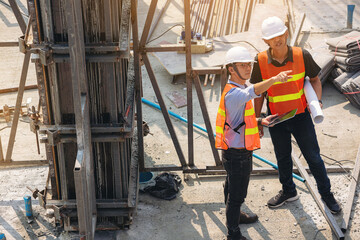 Naklejka na ściany i meble Structural engineer and foreman worker with blueprints discuss, plan inspecting for the outdoors building construction site.