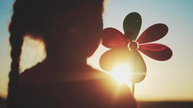 kid pinwheel. little baby girl silhouette play with windmill toy wind in the park. happy family kid dream concept. baby girl play toy pinwheel the glare sunset of fun the sun at in the park