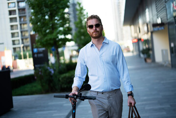 Young stylish businessman with e-scooter. Portrait of handsome man outdoors..