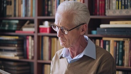 Mature male librarian reading book with interest, literature and knowledge