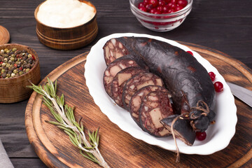 Traditional blood sausage on a white plate on a wooden board.