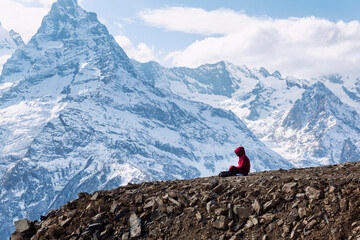 A man sits high in the mountains and meditates. Sports, active tourism and balance. Beautiful landscape.