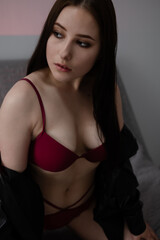 Fototapeta premium portrait of brunette woman in red underwear in dark grey room