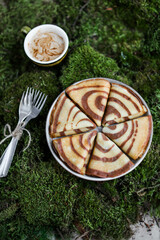 Pancakes with chocolate stripes in a gray plate. A plate of pancakes on a moss mat with cutlery and a cup of coffee.