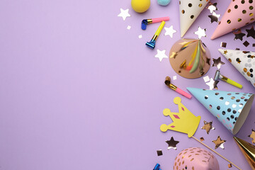 Flat lay composition with party hats and other festive items on violet background. Space for text
