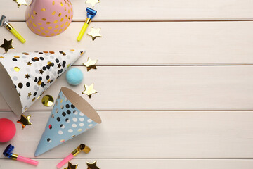 Flat lay composition with party hats and other festive items on white wooden background. Space for text