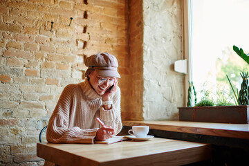 Fototapeta premium Happy woman talking on phone and writing notes