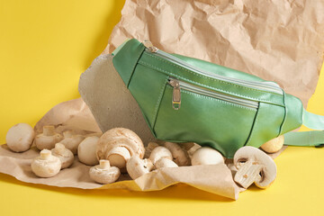 green belt bag made of eco leather and champignons on a yellow background, vegan leather concept