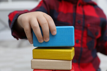 Little child playing with building blocks indoors, closeup