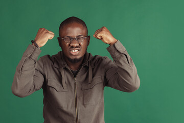 Winning success happy man celebrating being a winner. Dynamic image of male model isolated on dark green studio background