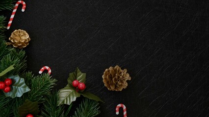  Top view christmas decorations, pine tree fir leaves, candy cane and red berries on dark black textured background